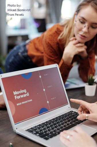 Image of woman looking at co-worker typing into a computer